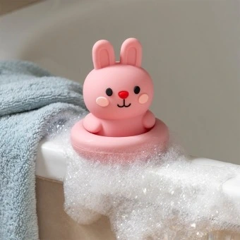 Pink silicone bunny bath toy with upright ears and simple face, in round base