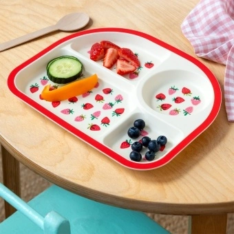 Strawberry-themed toddler divider plate shown with vegetables and fruits on a wooden table.