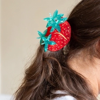 Hair claw clip featuring a sweet strawberry design in red, green and gold, with hints of marbling and translucence. 