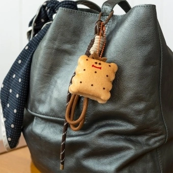 Plush toast bag charm with brown cord strap and metal clip attachment
