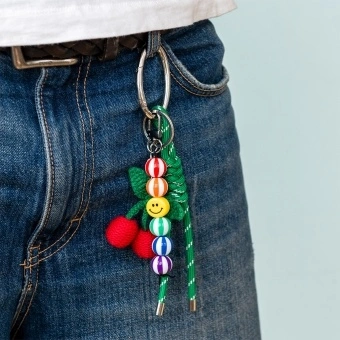 Crochet cherry bag charm with green cord strap, colourful beads