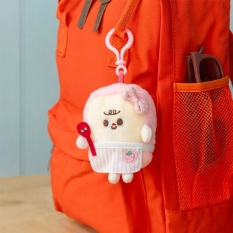 Plush toast bag charm with pink clip, pink spotty bow attached to the backpack