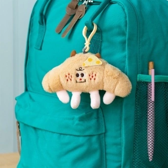 Fluffy croissant bag charm with smiley face, cheese patch and clip attachment