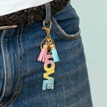 Gold keyring with colourful “LOVE” letter charm and pink and blue tassels.