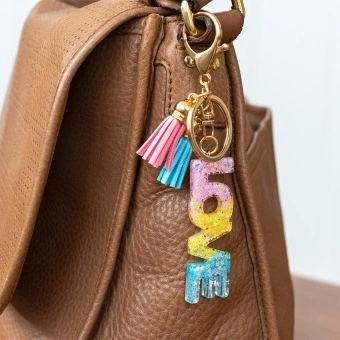 Gold keyring with colourful “LOVE” letter charm and pink and blue tassels.