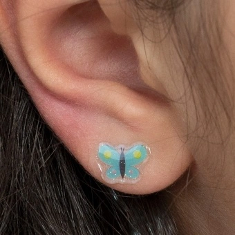 Stick-on earrings in butterfly shape on a kid’s ear