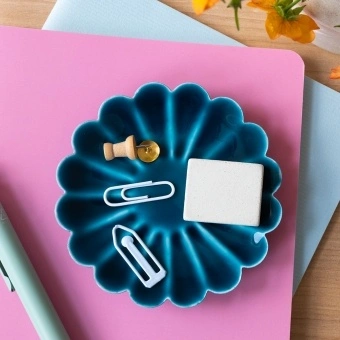 Blue enamel flower-shaped trinket dish holding clips and small items