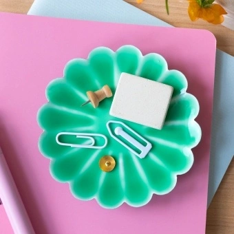 Green enamel flower-shaped trinket dish holding clips and small items