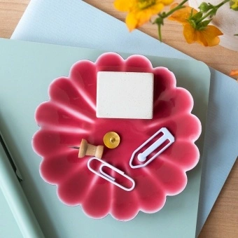 Red enamel flower-shaped trinket dish holding clips and small items