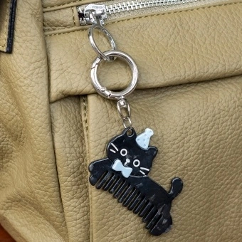 Black cat-shaped keyring with comb teeth, blue bow and hat attached to a silver ring.