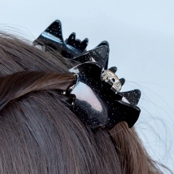 Set of two black glitter bat-shaped hair claw clips.
