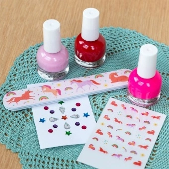 Unicorn nail kit contents including three nail polishes, a unicorn nail file, and unicorn-themed nail stickers.