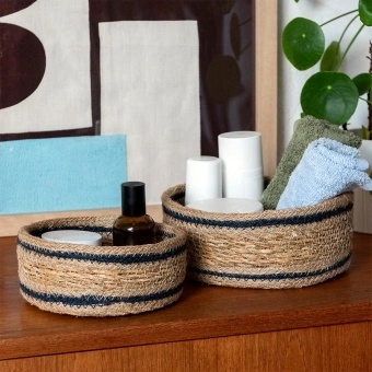 Set of two round woven storage baskets with black stripe detail.