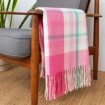 Check pattern in pink, white and teal blanket displayed over a wooden armchair