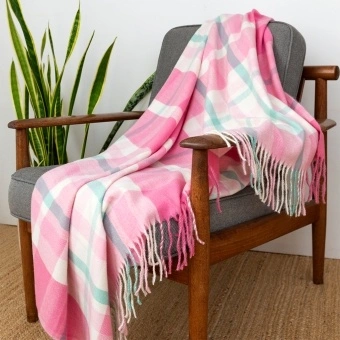 Check pattern in pink, white and teal blanket displayed over a wooden chair