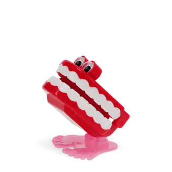 Wind-up toy shaped like red chattering teeth with white teeth, googly eyes, and pink feet