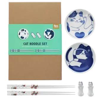 Two cat-themed dipping bowls, two pairs of chopsticks, and two cat-shaped rests beside a brown box.