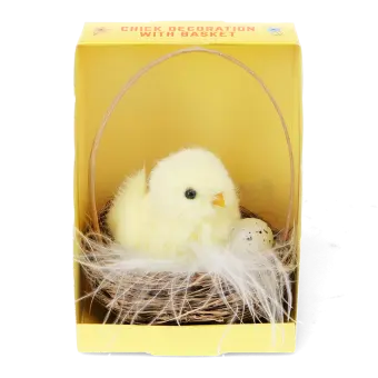 A fluffy yellow chick decoration sitting in a small wicker basket with an egg, displayed inside a yellow box.