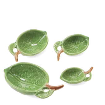 Set of four ceramic measuring spoons shaped like green leaves with brown stem handles 