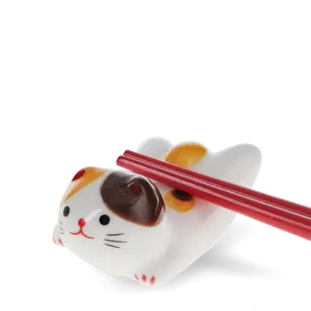 Chopsticks resting on a ceramic cat–shaped chopstick rest.