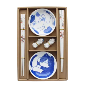 Two cat-themed dipping bowls, two pairs of chopsticks, and two cat-shaped rests in a brown box