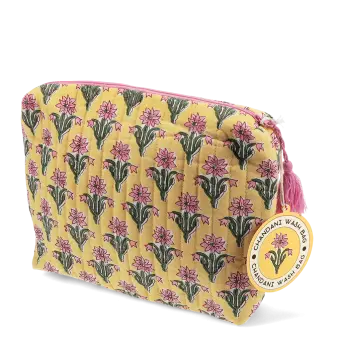 Yellow quilted wash bag with a pink and green flowers design and a tag.