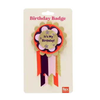 Colourful birthday badge with a gold centre reading ‘It’s My Birthday!’ and ribbons displayed with its packaging.