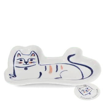 White ceramic trinket dish shaped like a reclining cat with a tag.