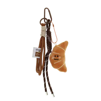 Plush croissant bag charm with brown cord strap and metal clip attachment