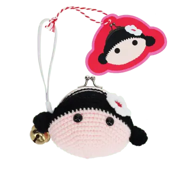 Crochet girl-shaped coin purse with a metal clasp and hanging bell charm with tag.