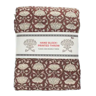 Brown hand block-printed throw with floral pattern, folded in packaging.